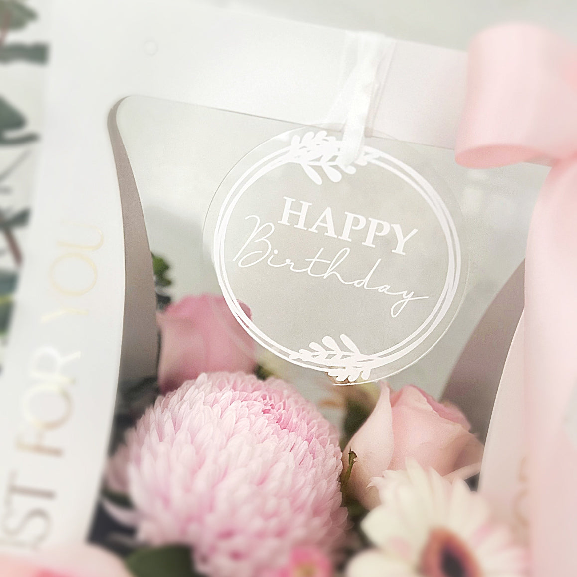 Round acrylic tag with happy birthday message added to flower arrangement with chrysanthemums, roses and gerberas.