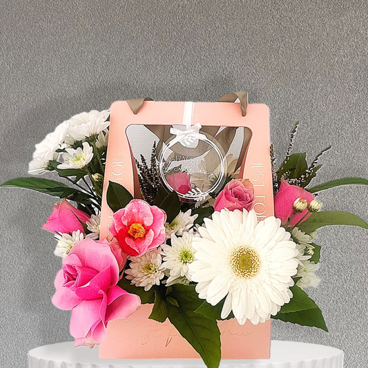 Pink and White Floral arrangement with a pink Carry Bag box and an acrylic Happy Birthday tag on a gray background