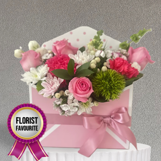 Floral arrangement in a pink box with a 'Florist Favourite' ribbon on a gray background
