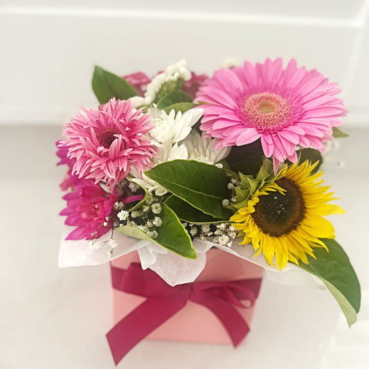 Bouquet of pink and yellow flowers with a pink bow on a white background