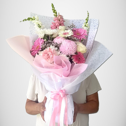 Large luxe pastel pink and white flower bouquet with gerberas, roses and chrysanthemums, wrapped in soft pink and white embossed papers and ribbons.